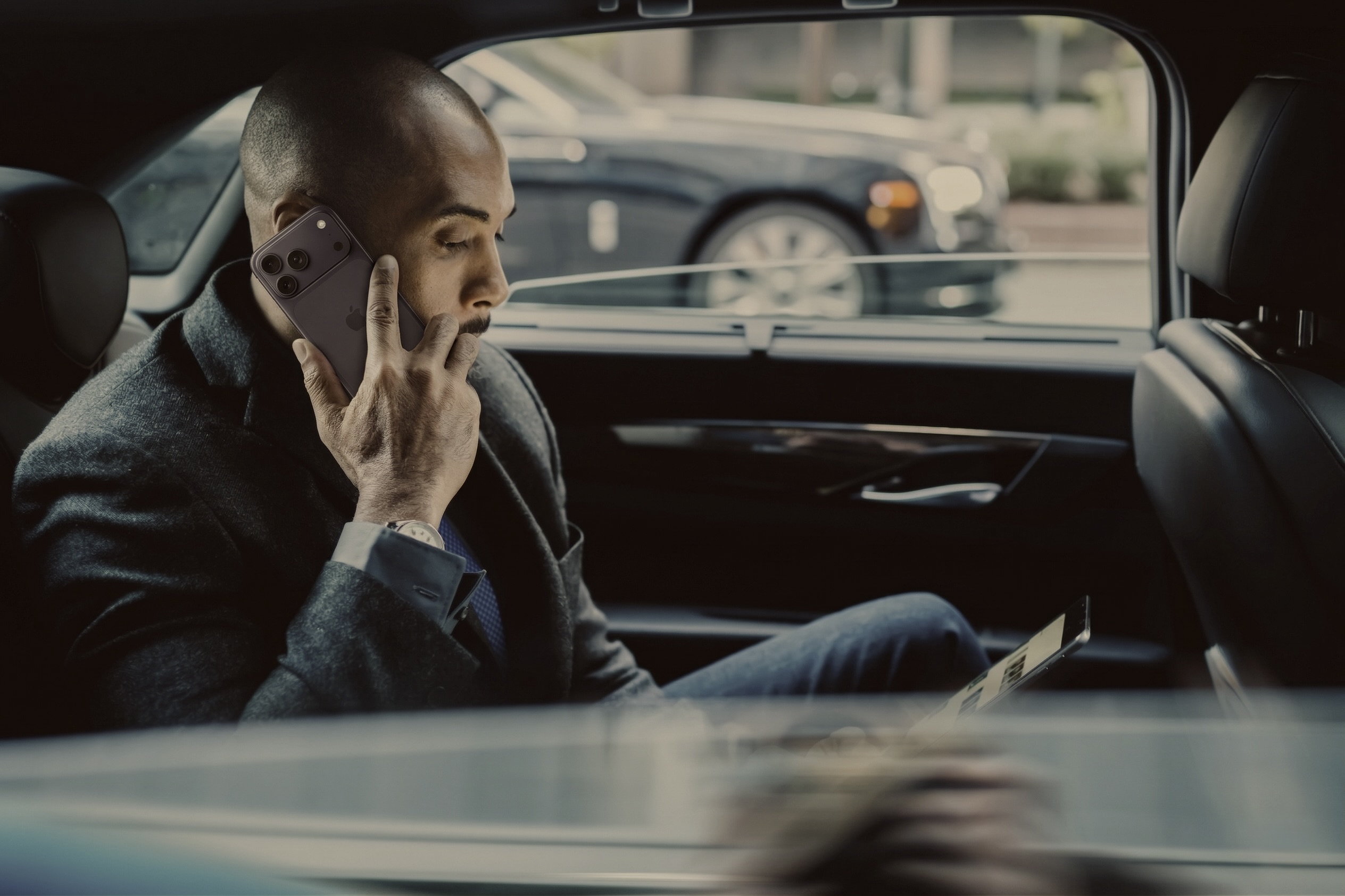 Executive on phone in rear of luxury chauffeur vehicle